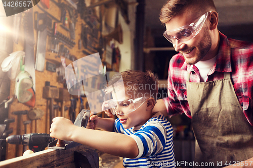 Image of father and son with plane shaving wood at workshop