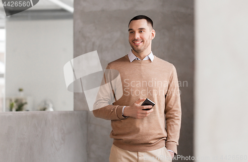 Image of smiling businessman with smartphone at office