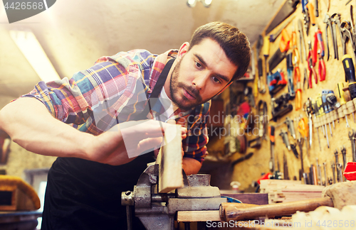 Image of carpenter working with plane and wood at workshop