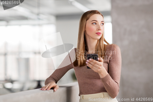 Image of happy businesswoman with smartphone at office