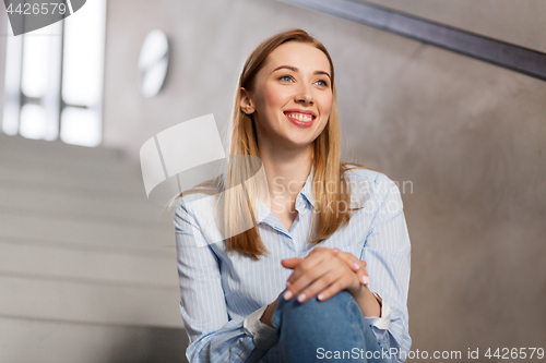 Image of happy smiling woman or student sitting on stairs