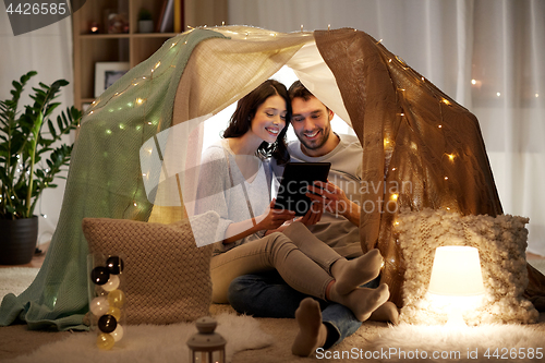 Image of happy couple with tablet pc in kids tent at home