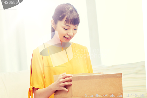 Image of happy asian young woman with parcel box at home