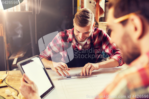 Image of workmen with tablet pc and blueprint at workshop