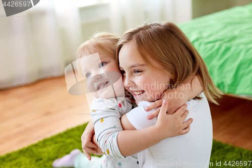 Image of happy little girls or sisters hugging at home