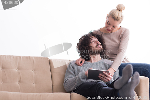 Image of couple relaxing at  home with tablet computers