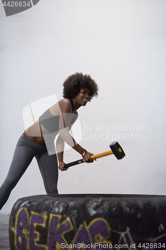 Image of black woman workout with hammer and tractor tire