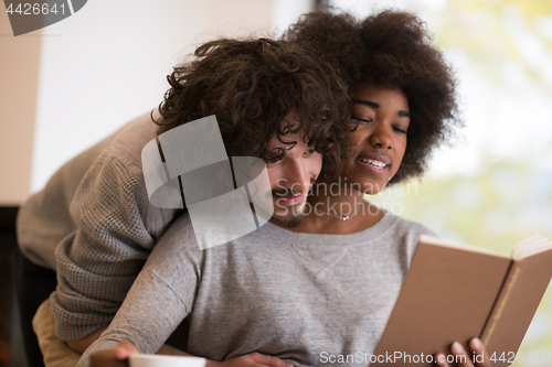 Image of multiethnic couple hugging in front of fireplace