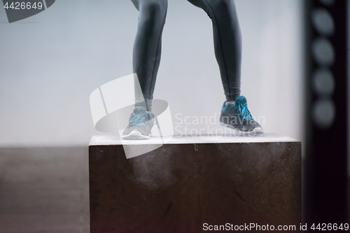 Image of black woman is performing box jumps at gym