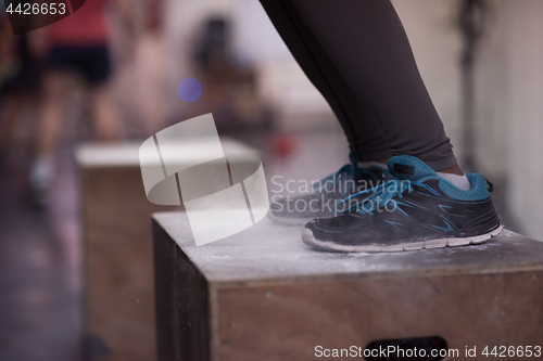 Image of black woman is performing box jumps at gym