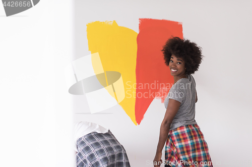 Image of multiethnic couple painting interior wall