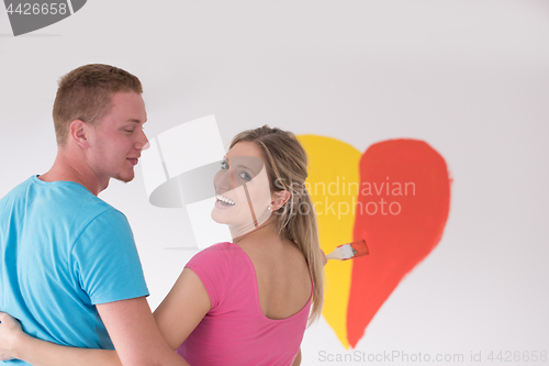 Image of couple are painting a heart on the wall