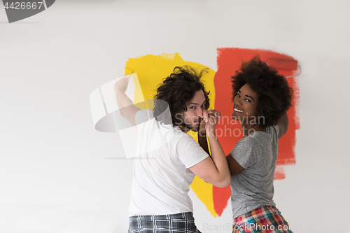 Image of multiethnic couple painting interior wall