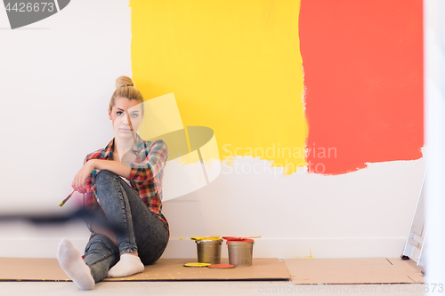 Image of young female painter sitting on floor