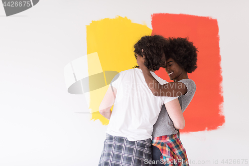 Image of multiethnic couple painting interior wall