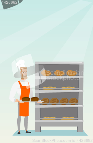 Image of Happy young baker holding a tray with bread.