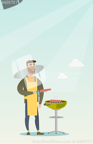 Image of Man cooking steak on barbecue grill.