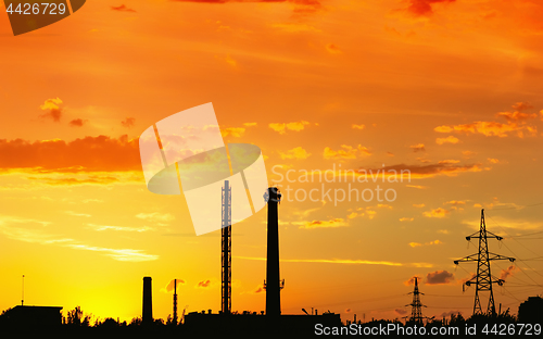 Image of Industrial landscape with silhouettes of pipes and towers agains