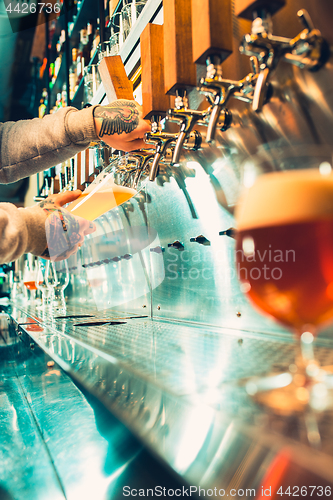 Image of Hand of bartender pouring a large lager beer in tap.