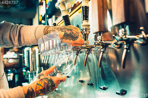 Image of Hand of bartender pouring a large lager beer in tap.