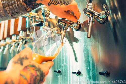 Image of Hand of bartender pouring a large lager beer in tap.