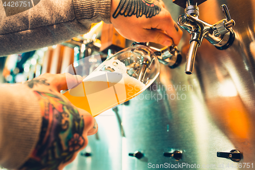 Image of Hand of bartender pouring a large lager beer in tap.