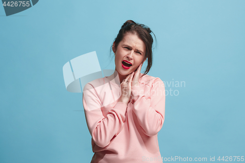 Image of The Ear ache. The sad woman with headache or pain on a blue studio background.