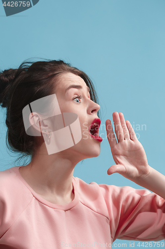 Image of Isolated on blue young casual woman shouting at studio