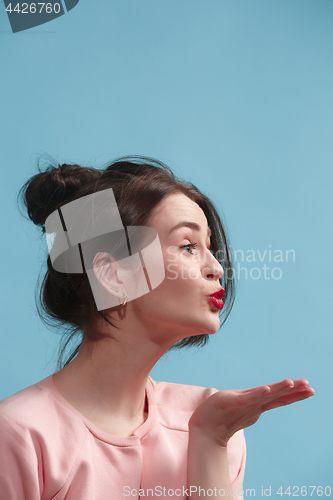 Image of Portrait of attractive cute girl with bright makeup with kiss isolated over blue background