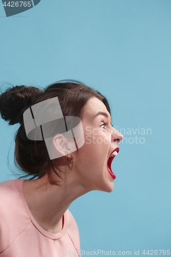 Image of The young emotional angry woman screaming on blue studio background