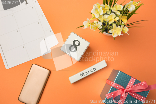 Image of The top view of orange desk with phone, gift, flowers and notebook