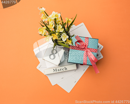 Image of The top view of orange desk with gift, flowers and notebook