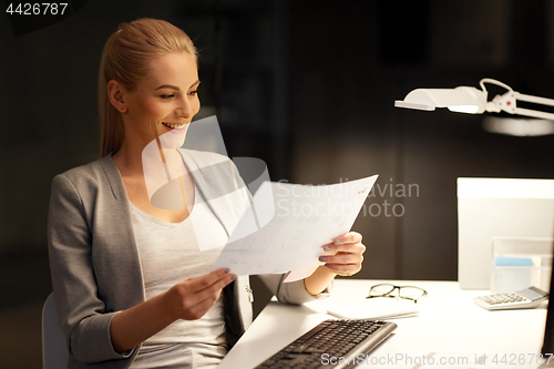 Image of businesswoman with papers working at night office