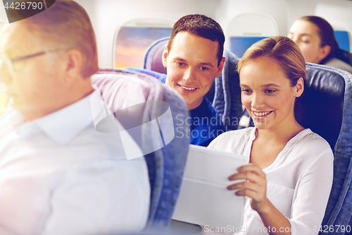 Image of happy passengers with coffee talking in plane