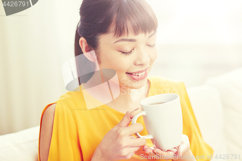 Image of happy asian woman drinking from tea cup