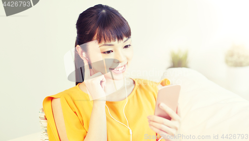 Image of happy asian woman with smartphone and earphones