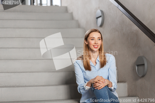 Image of happy smiling woman or student sitting on stairs