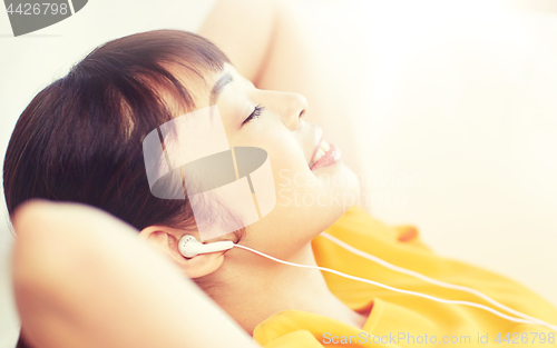 Image of happy asian woman with earphones listening music