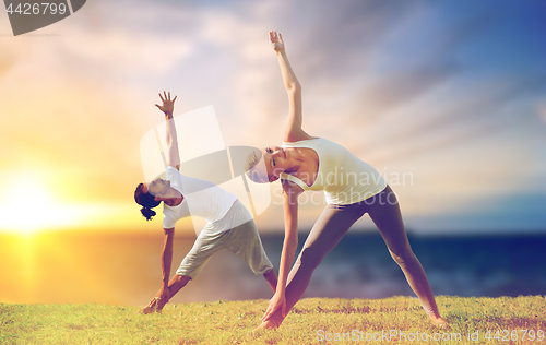 Image of couple making yoga triangle pose outdoors