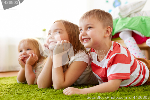 Image of happy little kids lying on floor or carpet