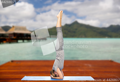 Image of woman making yoga in headstand pose outdoors