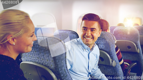 Image of happy passengers talking in plane