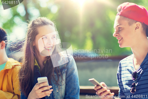 Image of happy teenage friends with smartphones outdoors