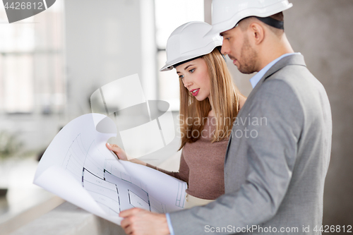 Image of architects with blueprint and helmets at office