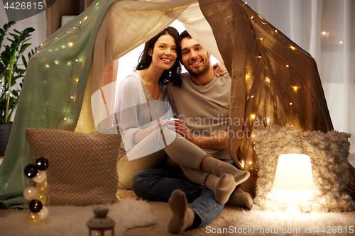 Image of happy couple in kids tent at home