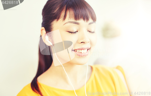 Image of happy asian woman with earphones listening music