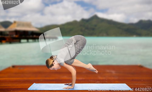 Image of woman making yoga in crane pose on mat outdoors