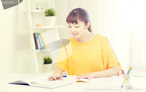 Image of happy asian young woman student learning at home