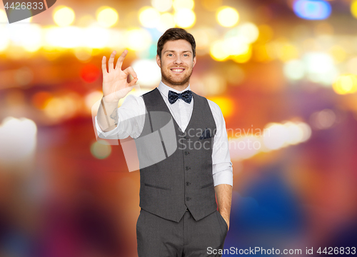 Image of man in suit showing ok sign over night city lights