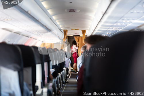 Image of Stewardess in red uniform on commercial passengers airplane.